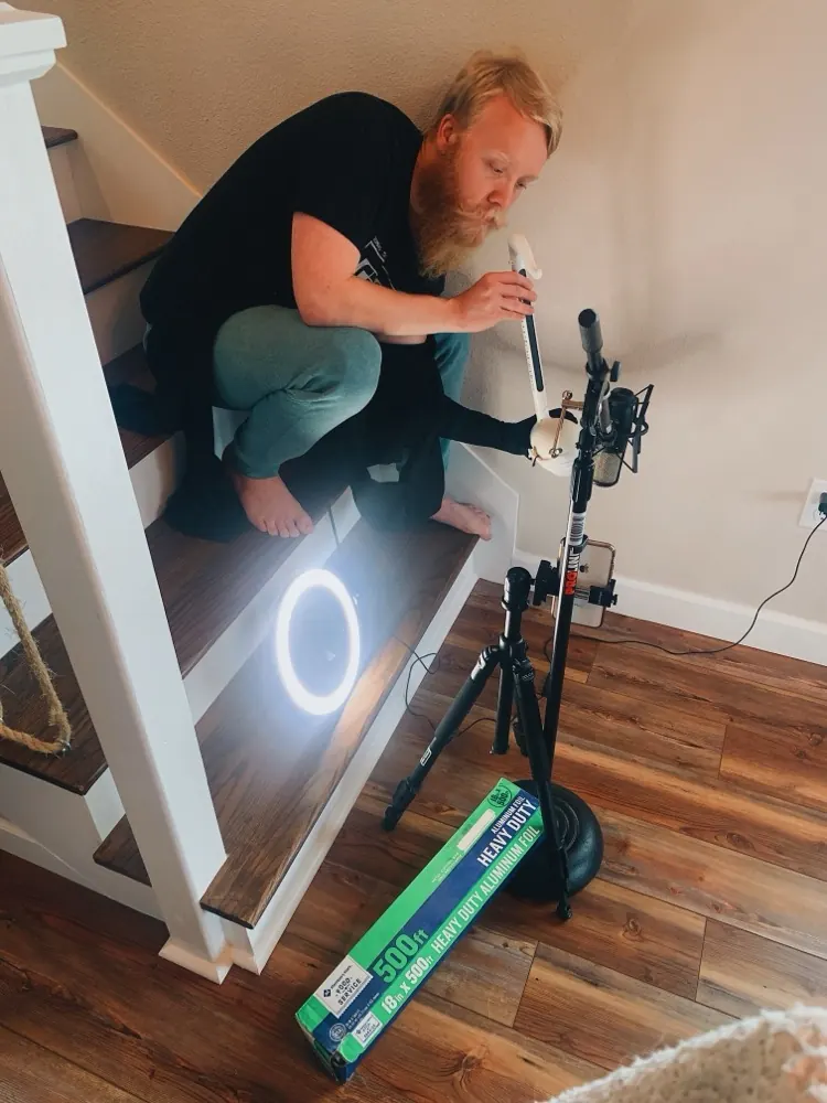 Cody setting up a phone, tripod, and ring light on the stairs for a social shoot